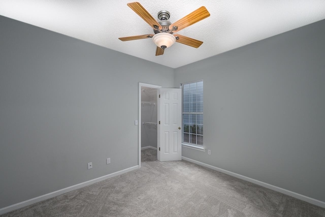 unfurnished bedroom featuring a spacious closet, ceiling fan, light colored carpet, and a closet