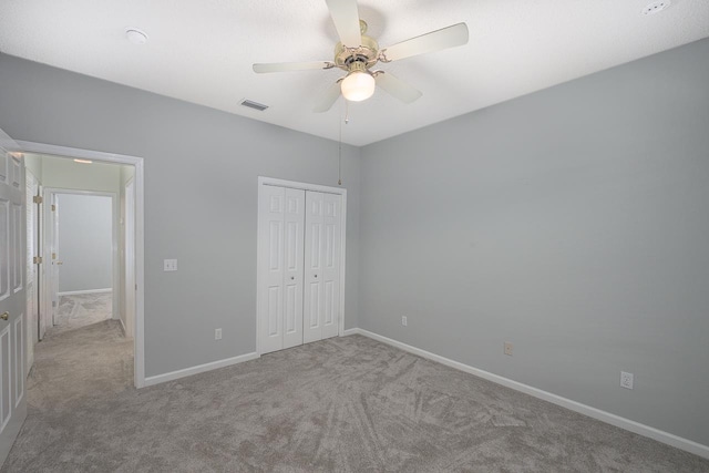 unfurnished bedroom featuring a closet, light carpet, and ceiling fan