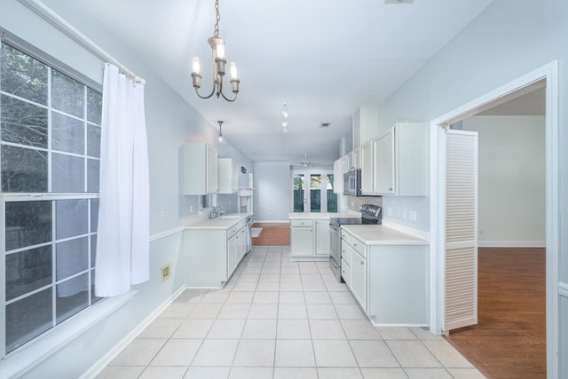 kitchen with appliances with stainless steel finishes, a notable chandelier, sink, white cabinets, and light hardwood / wood-style flooring