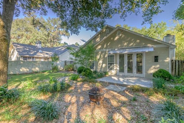 rear view of house with french doors, a fire pit, and a patio area