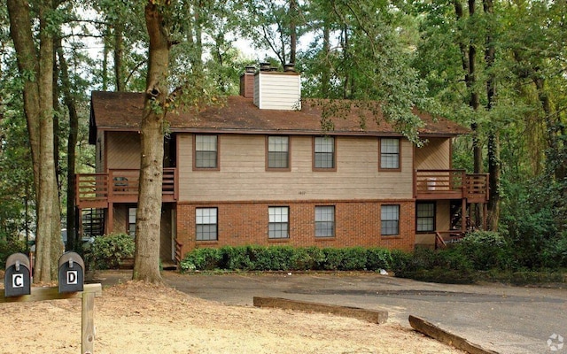 view of front of home with a chimney, a deck, and brick siding