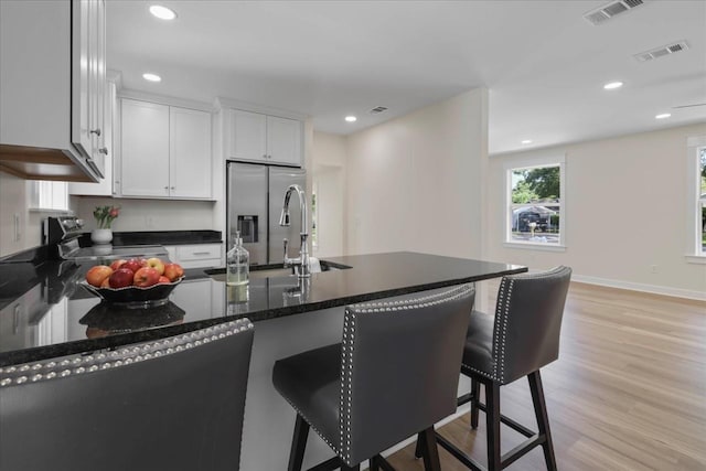1602 Carruthers St, Tallahassee, FL 32308 - kitchen with appliances with stainless steel finishes, a sink, light wood-style flooring, a breakfast bar area, and white cabinetry