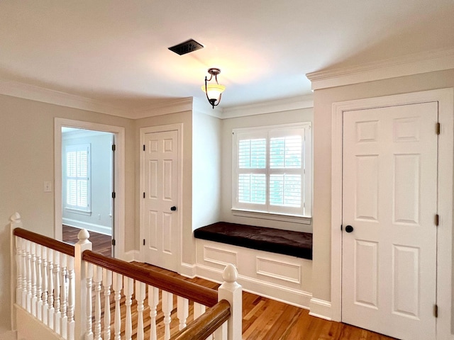 staircase with wood-type flooring, crown molding, and a healthy amount of sunlight