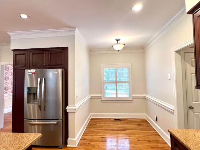 kitchen with stainless steel fridge, light wood-type flooring, dark brown cabinetry, and crown molding