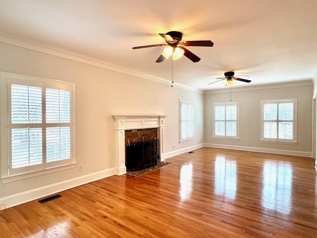 unfurnished living room with a brick fireplace, ceiling fan, crown molding, and light hardwood / wood-style flooring