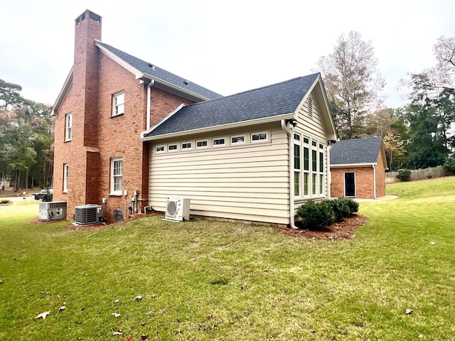 back of property with ac unit, central AC, and a lawn