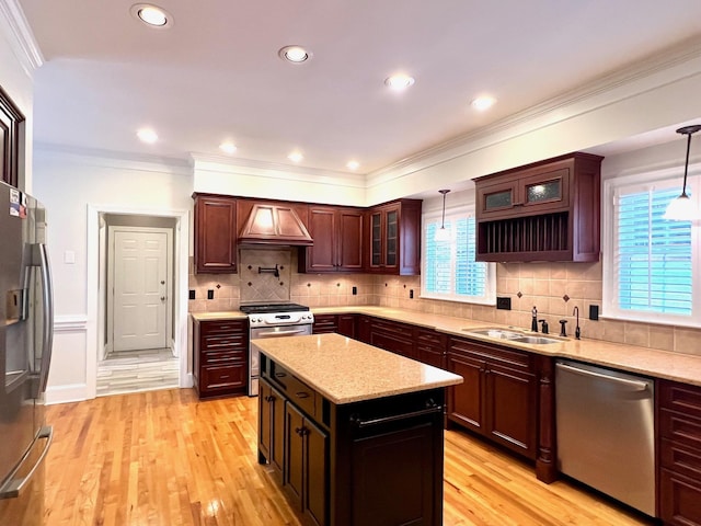 kitchen with sink, a kitchen island, decorative light fixtures, light hardwood / wood-style floors, and stainless steel appliances