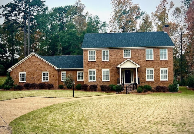 colonial-style house featuring a front lawn