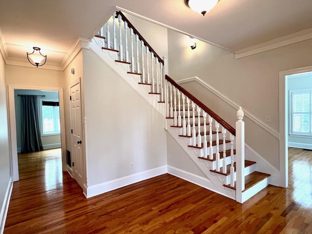 staircase with crown molding, plenty of natural light, and wood-type flooring