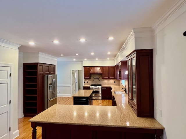 kitchen with kitchen peninsula, appliances with stainless steel finishes, crown molding, sink, and light hardwood / wood-style floors