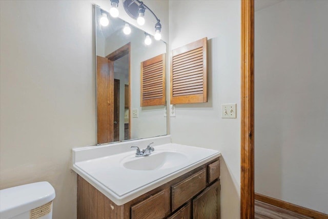 bathroom featuring wood-type flooring, vanity, and toilet