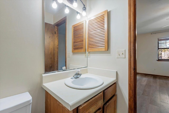 bathroom with wood-type flooring, vanity, and toilet