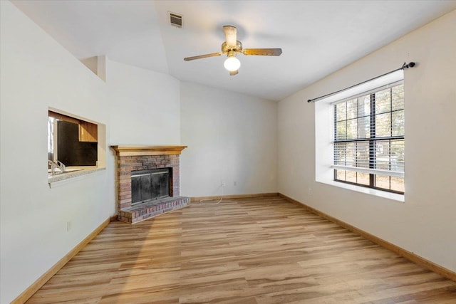 unfurnished living room with a brick fireplace, ceiling fan, vaulted ceiling, and light wood-type flooring