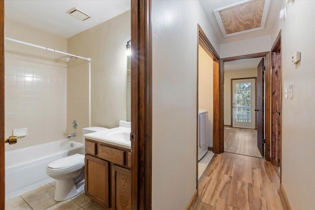 full bathroom with vanity, tiled shower / bath combo, hardwood / wood-style flooring, washer / dryer, and toilet