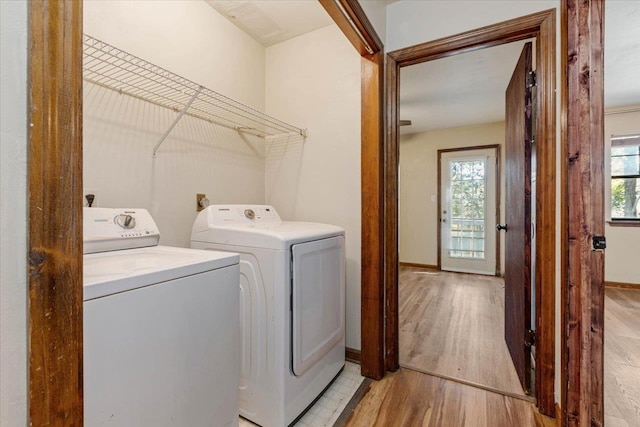 washroom with light hardwood / wood-style floors, a healthy amount of sunlight, and washing machine and clothes dryer