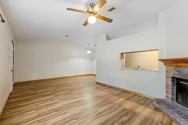 unfurnished living room with a brick fireplace, light hardwood / wood-style flooring, vaulted ceiling, and ceiling fan