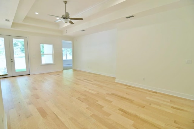 empty room featuring ceiling fan, french doors, light hardwood / wood-style floors, and a raised ceiling