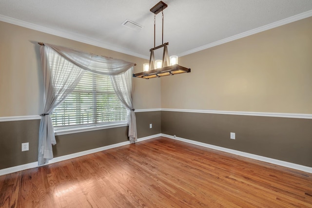 unfurnished room featuring crown molding, a notable chandelier, baseboards, wood finished floors, and visible vents