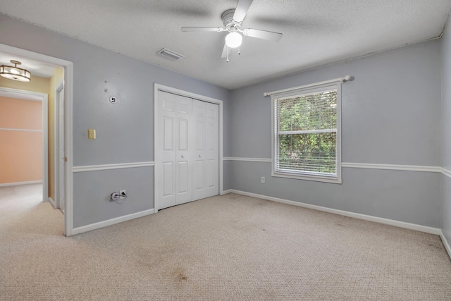 unfurnished bedroom with carpet, a closet, a textured ceiling, and visible vents