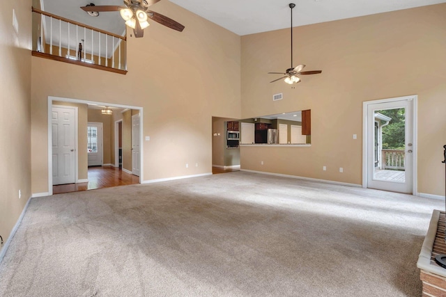 unfurnished living room featuring plenty of natural light, ceiling fan, and carpet