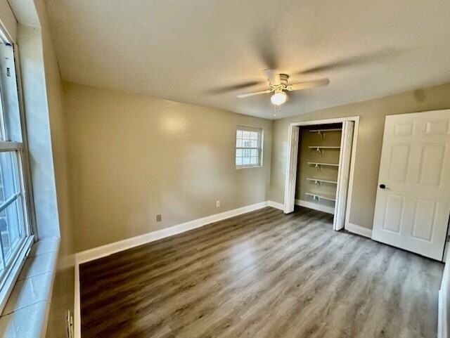 unfurnished bedroom featuring wood-type flooring, ceiling fan, and a closet