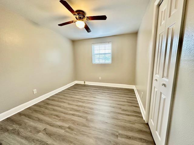 unfurnished bedroom featuring hardwood / wood-style flooring, ceiling fan, and a closet