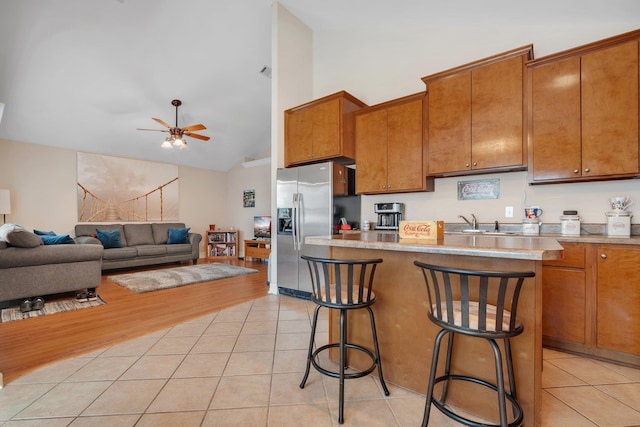 kitchen featuring light tile patterned floors, a kitchen breakfast bar, ceiling fan, and stainless steel refrigerator with ice dispenser