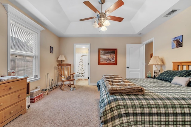 carpeted bedroom with a raised ceiling and ceiling fan