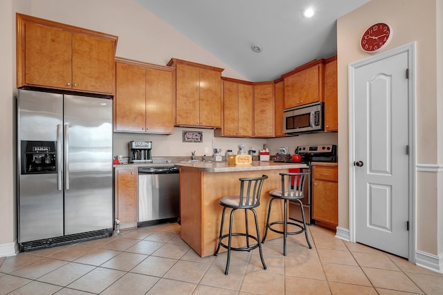 kitchen featuring light tile patterned flooring, appliances with stainless steel finishes, a kitchen breakfast bar, and a center island