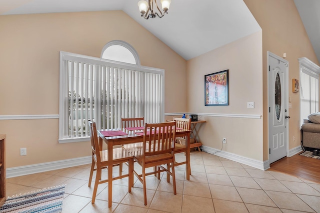 tiled dining area with vaulted ceiling and a chandelier