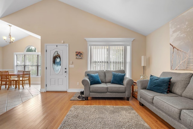 living room with high vaulted ceiling, a notable chandelier, and light hardwood / wood-style floors