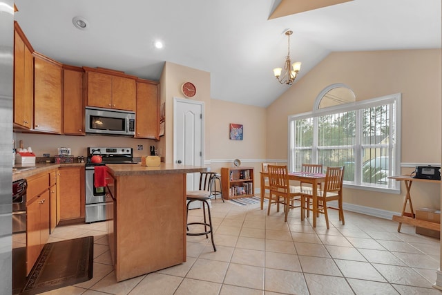 kitchen with a kitchen island, appliances with stainless steel finishes, lofted ceiling, a kitchen bar, and an inviting chandelier