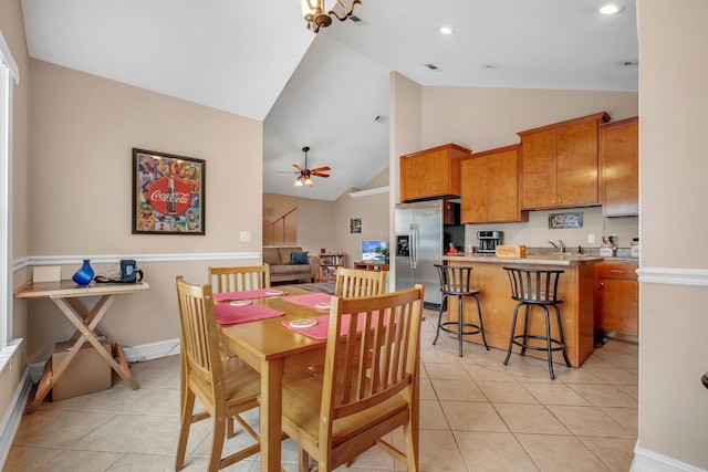 tiled dining area with ceiling fan and high vaulted ceiling