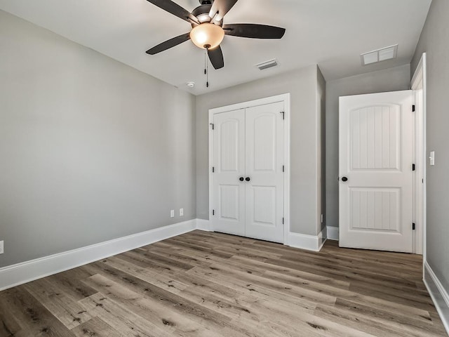 unfurnished bedroom featuring hardwood / wood-style flooring, a closet, and ceiling fan