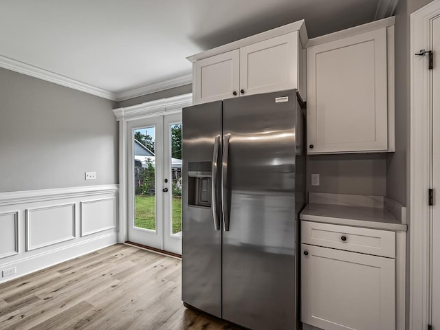 kitchen with stainless steel refrigerator with ice dispenser, french doors, crown molding, light hardwood / wood-style floors, and white cabinets