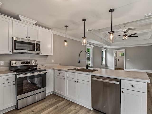 kitchen with sink, appliances with stainless steel finishes, hanging light fixtures, white cabinets, and kitchen peninsula