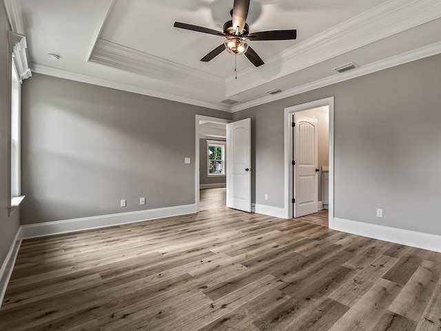 unfurnished bedroom featuring wood-type flooring, ornamental molding, a raised ceiling, and ceiling fan