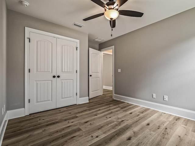 unfurnished bedroom featuring ceiling fan, dark hardwood / wood-style floors, and a closet