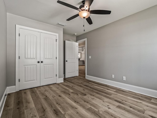 unfurnished bedroom with light wood-type flooring, ceiling fan, and a closet