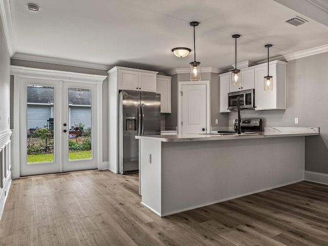 kitchen featuring stainless steel appliances, hanging light fixtures, white cabinets, and kitchen peninsula