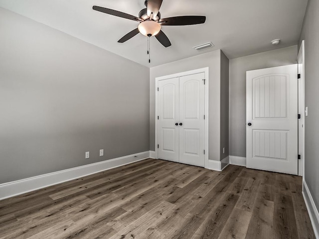 unfurnished bedroom with dark hardwood / wood-style floors, ceiling fan, and a closet