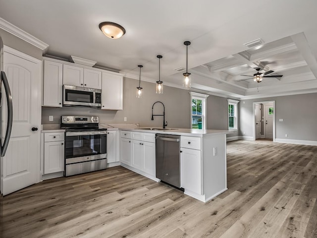 kitchen featuring pendant lighting, sink, appliances with stainless steel finishes, white cabinetry, and kitchen peninsula