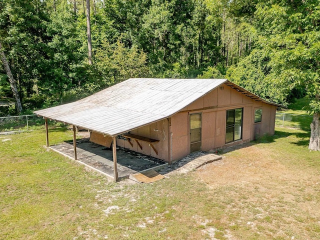 view of outbuilding featuring driveway, fence, and a carport