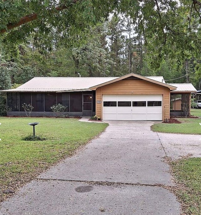 single story home featuring aphalt driveway, a front yard, a sunroom, and a garage