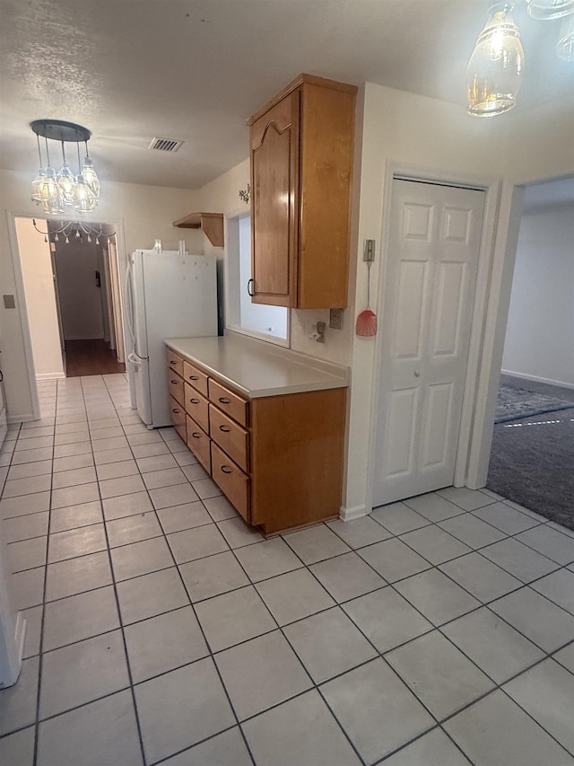 kitchen featuring pendant lighting, light countertops, visible vents, freestanding refrigerator, and light tile patterned flooring