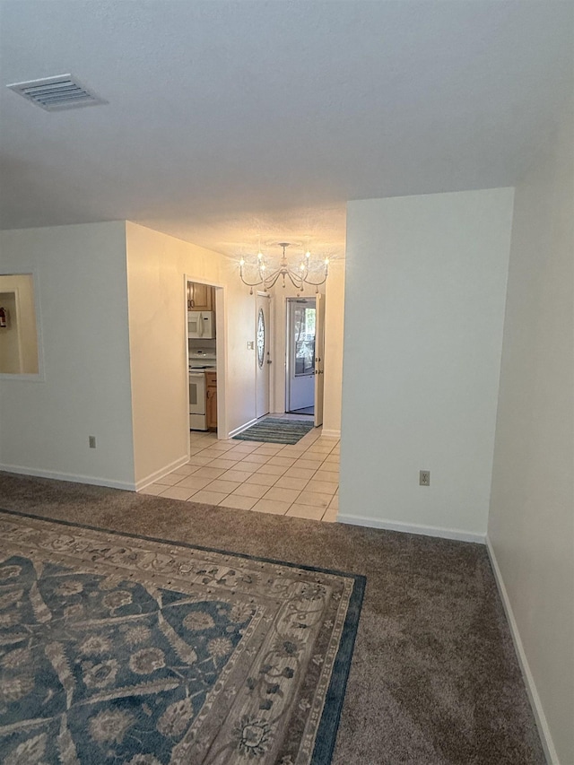 spare room with light tile patterned floors, light colored carpet, visible vents, a chandelier, and baseboards