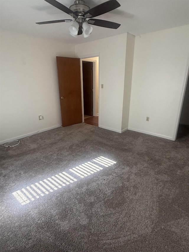 unfurnished room featuring dark carpet and baseboards