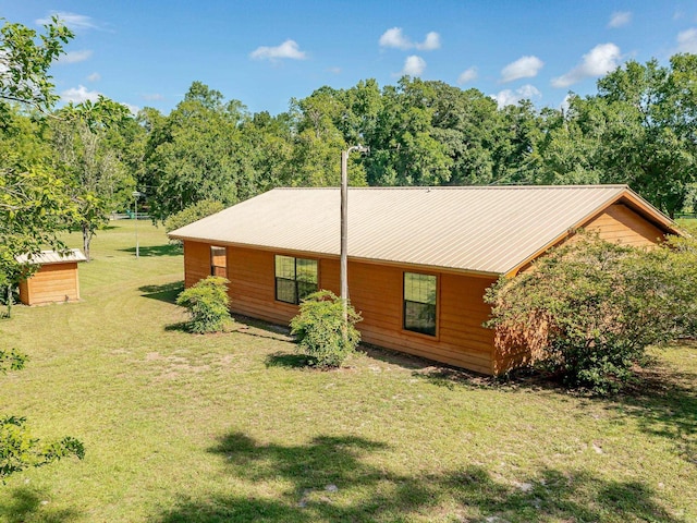 back of house featuring metal roof and a lawn