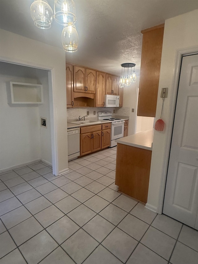 kitchen featuring light countertops, white appliances, a sink, and pendant lighting