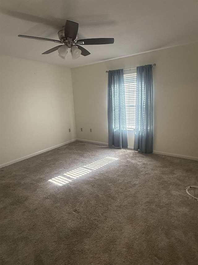 empty room with a ceiling fan, dark colored carpet, and baseboards